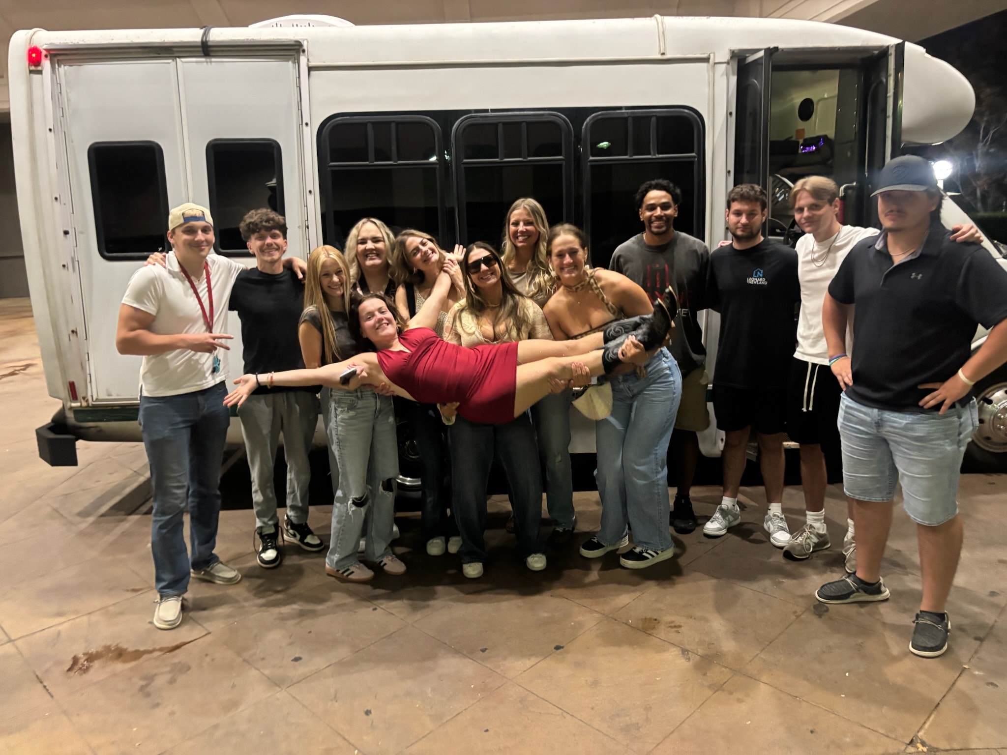 Group of friends posing outside the party bus at night, arms around each other after a celebration