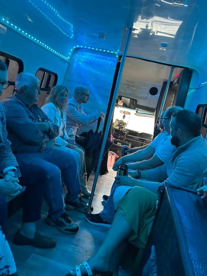 Inside the party bus at night with blue LED lights and passengers seated along the leather benches